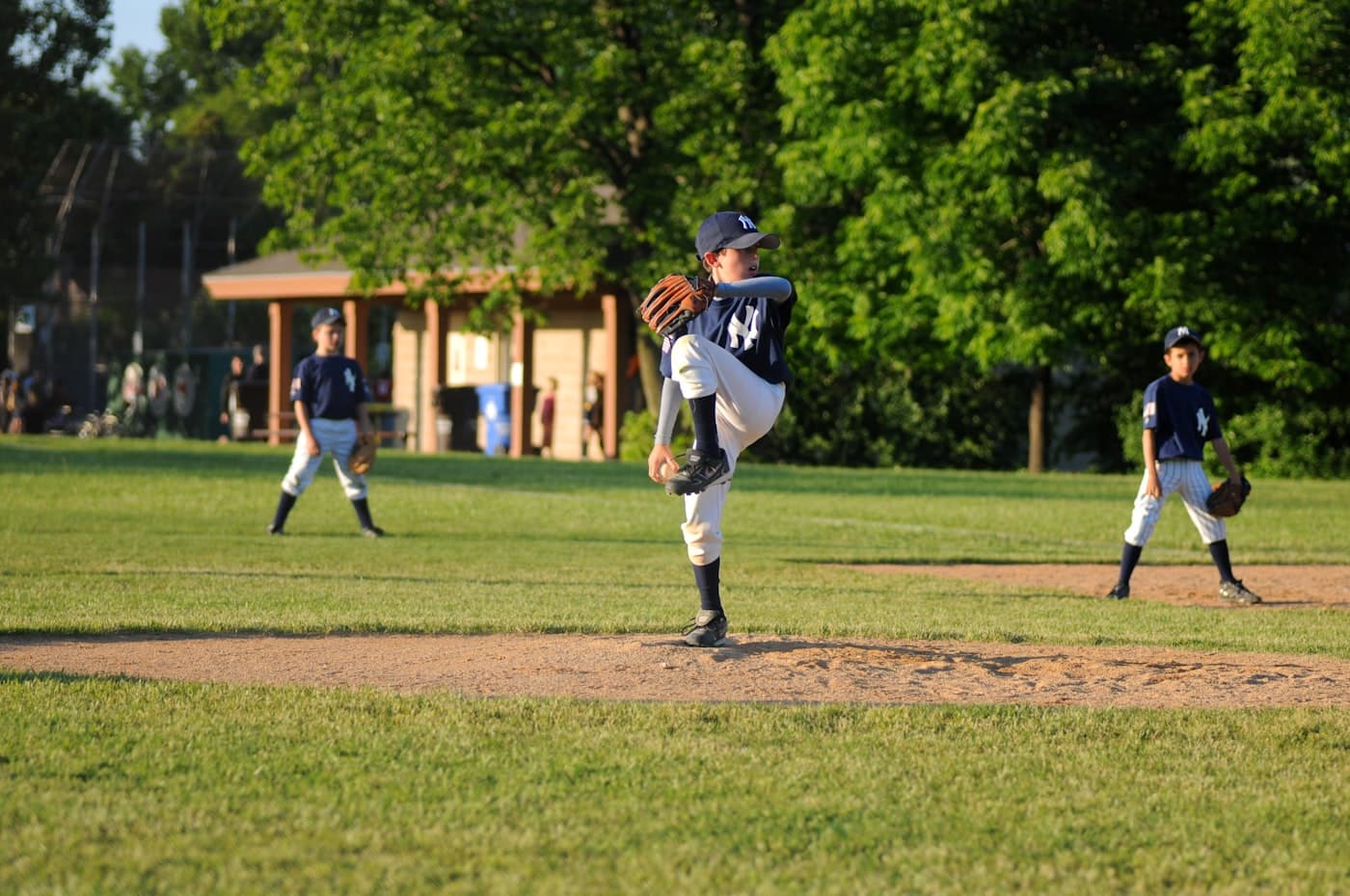 A youth pitcher mid-windup on a neighborhood field.